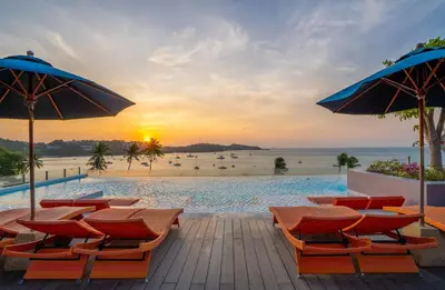 a pool at the beach with chairs and umbrellas at Bandara Beach Resort, Phuket in Panwa Beach