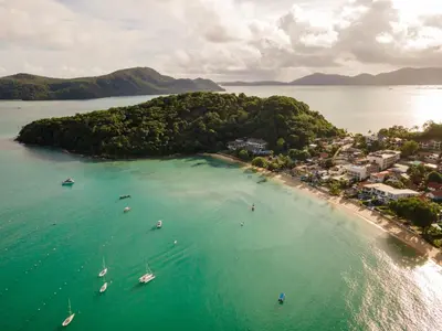 an island in the ocean with boats in the water at Bandara Beach Resort, Phuket in Panwa Beach