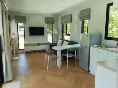 a kitchen and living room with a table and a refrigerator at Little Sweet Home in Phuket Town