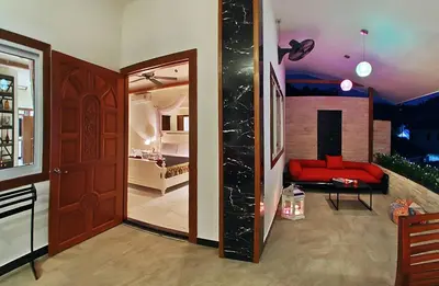 a living room with a red couch and a door at Baan Sung Apartments in Kamala Beach