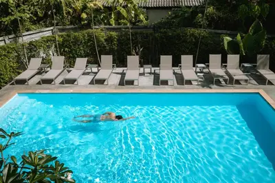 a person swimming in a swimming pool with chairs at Seaside Naithon Phuket - Newly Opened in Nai Thon Beach