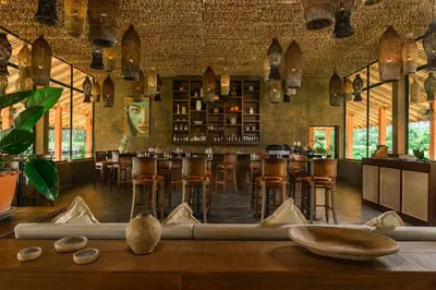 a restaurant with a bar with wooden tables and stools at Niran Farm in Koh Lone