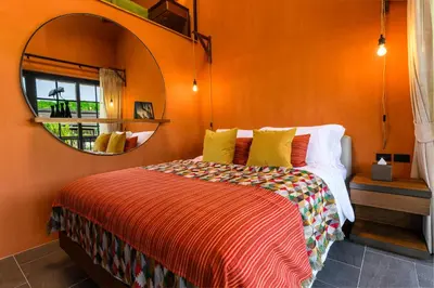 a bedroom with an orange wall with a bed and a mirror at Niran Farm in Koh Lone