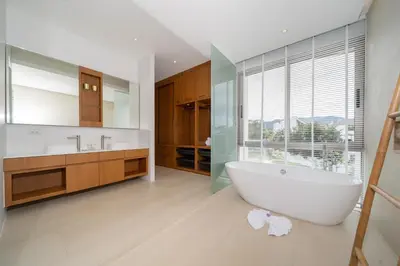 a bathroom with a white tub and a large window at Modern Masterpiece with Tropical Flair! 5BR Villa Trinity C4 in Bang Tao Beach