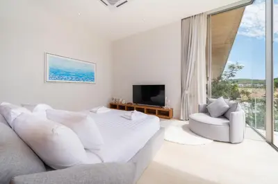 a white bedroom with a couch and a tv at Modern Masterpiece with Tropical Flair! 5BR Villa Trinity C4 in Bang Tao Beach