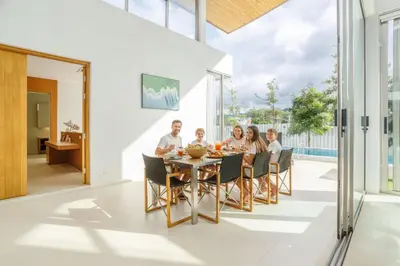a family sitting around a dining room table in a house at Brand-New & Luxury 5BR Pool Villa Trinity C2 in Bang Tao Beach