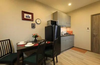 a kitchen with a table and a black refrigerator at Mountain View Apart Naiyang Beach in Phuket