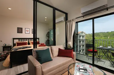 a bedroom with a couch and a bed and a balcony at Mountain View Apart Naiyang Beach in Phuket