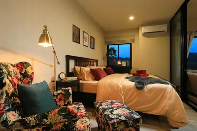 a bedroom with a bed and a couch and chairs at Mountain View Apart Naiyang Beach in Phuket