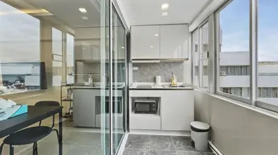 a kitchen with white cabinets and a desk and windows at Heritage - Modern Studio shared Pool, City Centre in Patong Beach