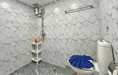 a white tiled bathroom with a toilet in it at Heritage - Modern Studio shared Pool, City Centre in Patong Beach