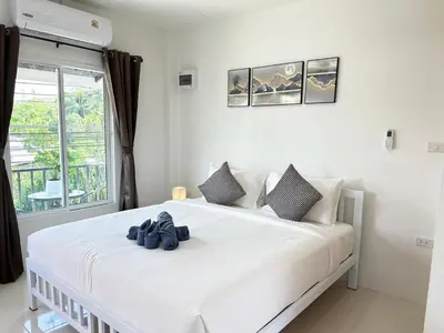 a white bedroom with a large white bed with blue shoes on it at Sachi House Stay Near Muay Thai Gym and Beach in Ban Thalat Choeng Thale