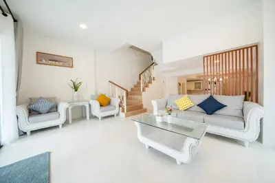 a living room with white furniture and a staircase at New Charming Patong Pool villa 5 mins walk Bangla beach in Patong Beach