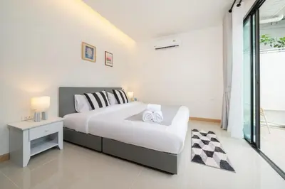 a white bedroom with a large bed and a table at New Charming Patong Pool villa 5 mins walk Bangla beach in Patong Beach