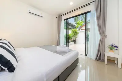 a white bedroom with a bed and a large window at New Charming Patong Pool villa 5 mins walk Bangla beach in Patong Beach