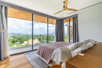 a bedroom with a large bed and large windows at La Vista by Villacarte in Chalong