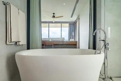 a white bath tub in a bathroom with a bedroom at La Vista by Villacarte in Chalong