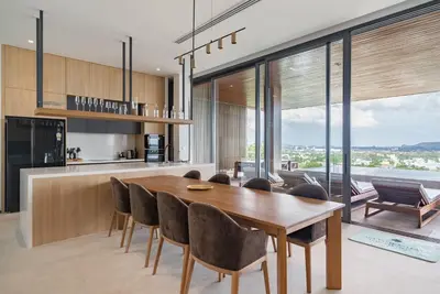 a kitchen and dining room with a wooden table and chairs at La Vista by Villacarte in Chalong