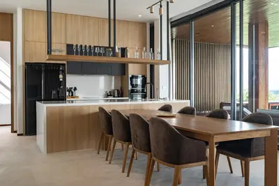 a kitchen and dining room with a wooden table and chairs at La Vista by Villacarte in Chalong
