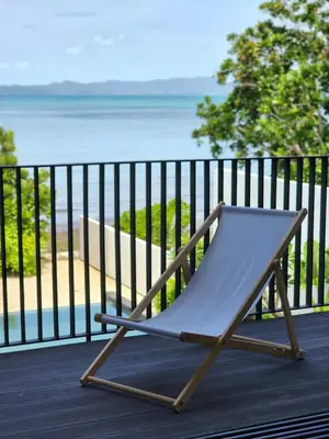 a chair sitting on a deck overlooking the ocean at Luxury Beachfront BRAHMA Villa 4 Br at Ta-Ke Residence B in Phuket