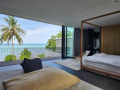 a bedroom with a bed and a view of the ocean at Luxury Beachfront BRAHMA Villa 4 Br at Ta-Ke Residence B in Phuket