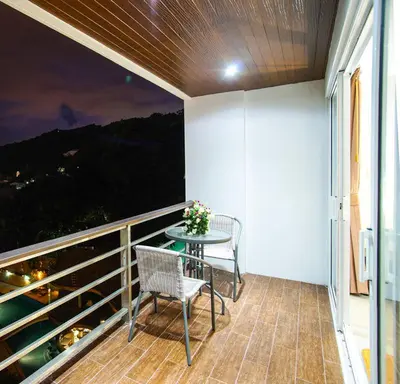 a balcony with two chairs and a table with a view at Large, Quiet Corner Condo in Patong Beach