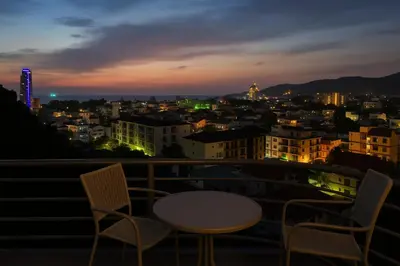 a table and chairs on a balcony at night at Large, Quiet Corner Condo in Patong Beach