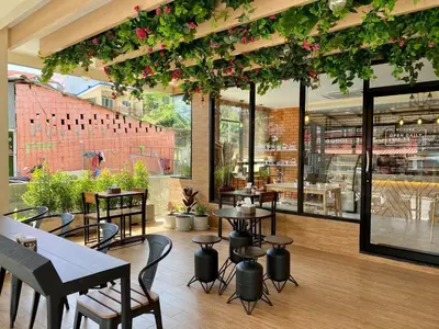 a restaurant with tables and chairs and plants at Mildmint มายมิ้นท์อพาร์ทเม้นท์ Self Serviced in Kata Beach