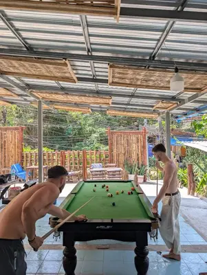 two men playing pool on a pool table at Hangover Chill & Hill Hostel in Phi Phi Don