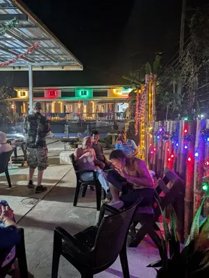 a group of people sitting in chairs in front of a bar at Hangover Chill & Hill Hostel in Phi Phi Don