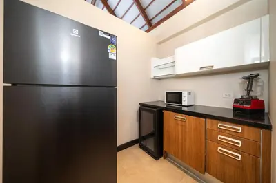 a large black refrigerator in a kitchen with wooden cabinets at Luxurious Villa Near Bangtao Beach in Bang Tao Beach