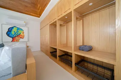 a walk in closet with wooden cabinets at Elite Living - Design 3BR Pool Villa in Newly Built LuxPride 4 L6 Residence in Bang Tao Beach