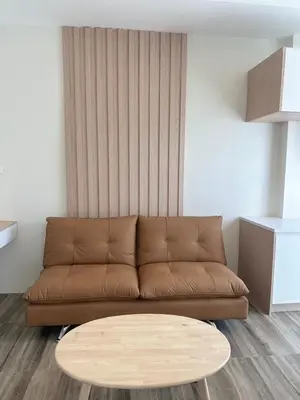 a living room with a brown couch and a coffee table at Sleep At Airport in Nai Yang Beach