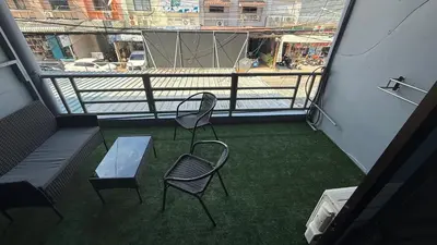 a balcony with two chairs and a glass table at Chalong Paradise Guesthouse in Ban Bang Chak