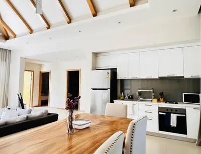 a kitchen and living room with a wooden table and chairs at Trichada Sky 3bed villa, Bangtao, Laguna in Phuket