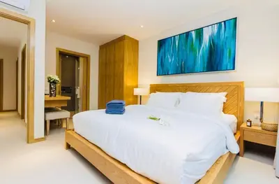 a bedroom with a large white bed with a large painting on the wall at Trichada Sky 3bed villa, Bangtao, Laguna in Phuket