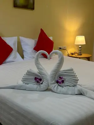 two swans shaped like hearts sitting on a bed at Theclickguesthouse in Ban Bang Chak