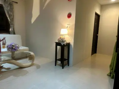 a bathroom with a toilet and a table with flowers on it at Theclickguesthouse in Ban Bang Chak