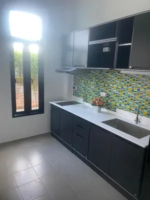 a kitchen with black cabinets and a sink and a window at Phuket Mali house in Ban Sam Kong