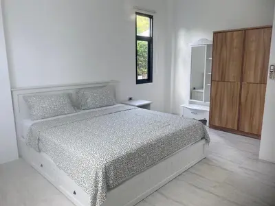 a white bedroom with a bed and a window at Phuket Mali house in Ban Sam Kong