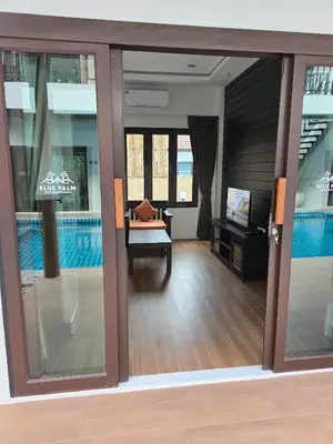 a view of a living room with a pool through sliding glass doors at Blue Palm Residence Kata in Kata Beach