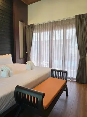 a bedroom with two beds and a bench in front of a window at Blue Palm Residence Kata in Kata Beach