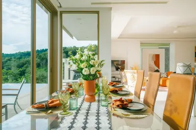 a dining room with a glass table with flowers on it at Seaview Villa Near Naithon Beach Phuket in Nai Thon Beach