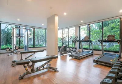 a gym with a bunch of cardio equipment in a room with windows at The Title Residencies Naiyang in Phuket