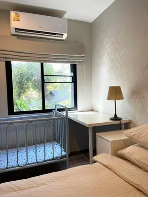 a bedroom with a crib and a desk and a window at The Title Residencies Naiyang in Phuket
