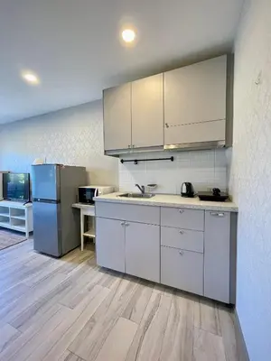 a kitchen with white cabinets and a refrigerator at The Title Residencies Naiyang in Phuket