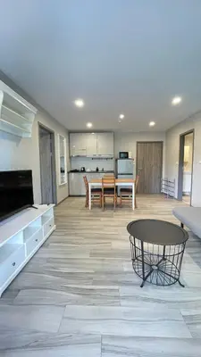 a large living room with a table and a kitchen at The Title Residencies Naiyang in Phuket
