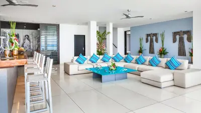 a living room with white furniture and blue pillows at Ocean's 11 Villa in Thalang