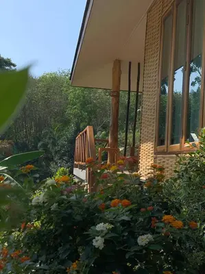 a wooden bench sitting outside of a house with flowers at Thiwson Beach Resort - SHA Extra Plus in Ko Yao Yai