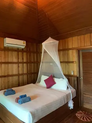 a bed in a wooden room with two towels on it at Thiwson Beach Resort - SHA Extra Plus in Ko Yao Yai